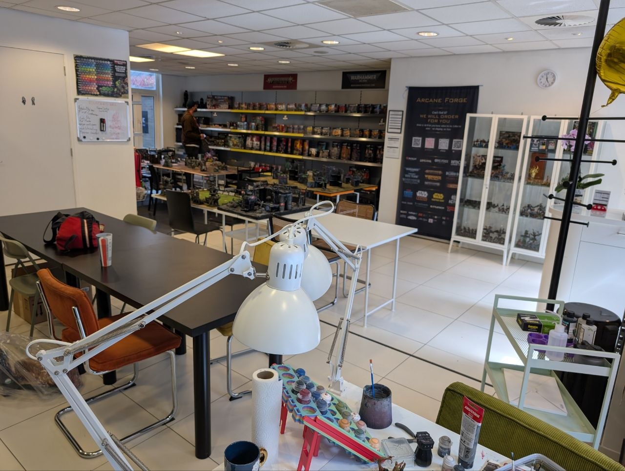 Interior of a hobby shop with tables, chairs, and shelves stocked with products.